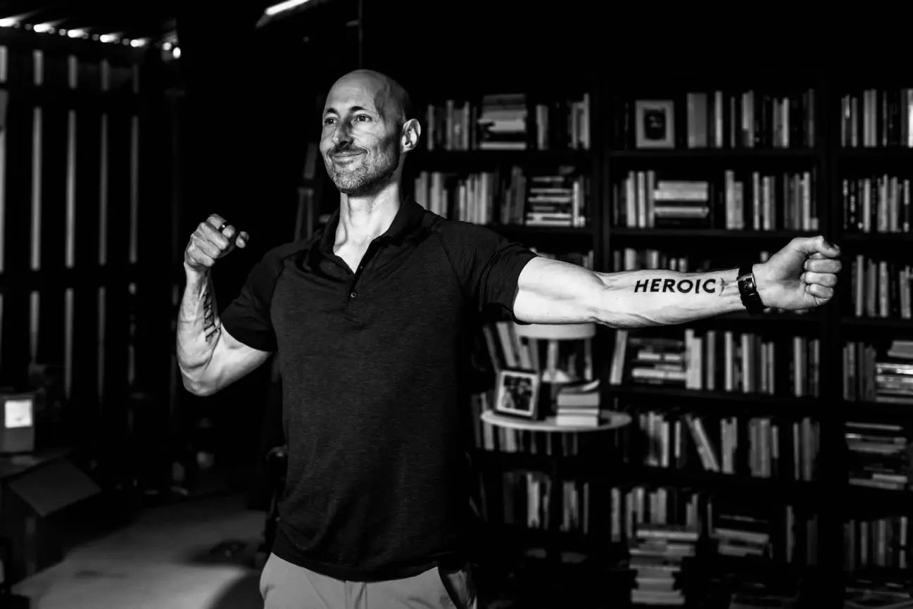 Brian Johnson standing in his library with his arms outstretched
