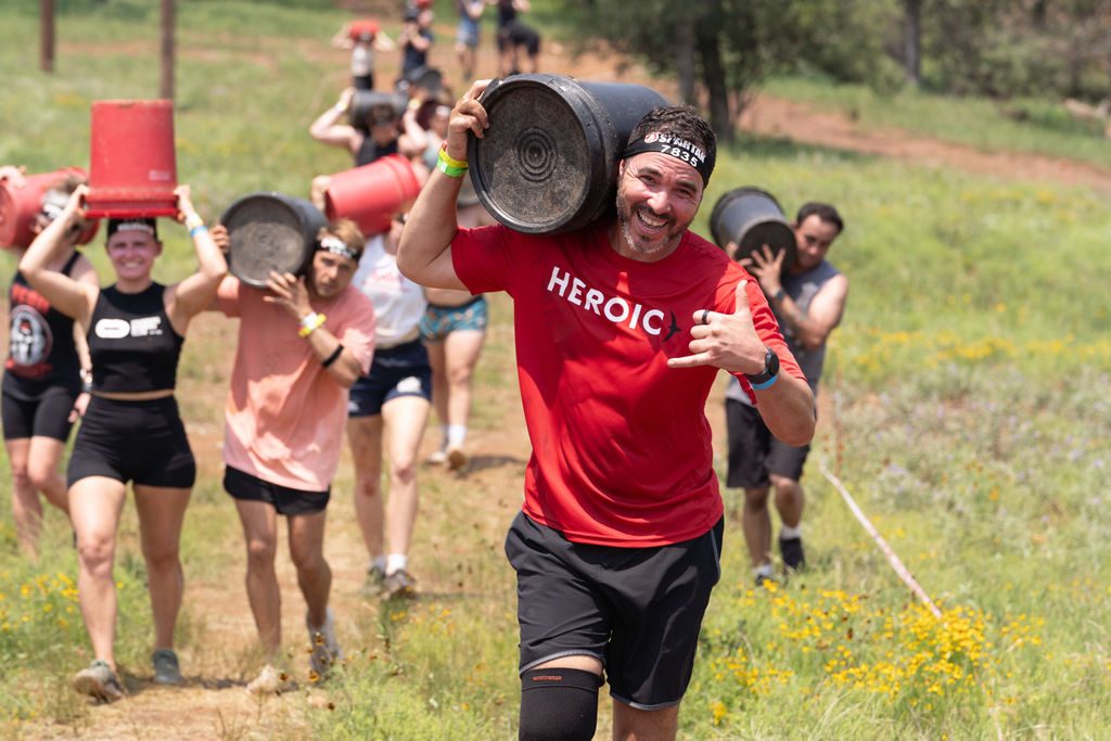 Heroic members carrying buckets up a hill together at a live event