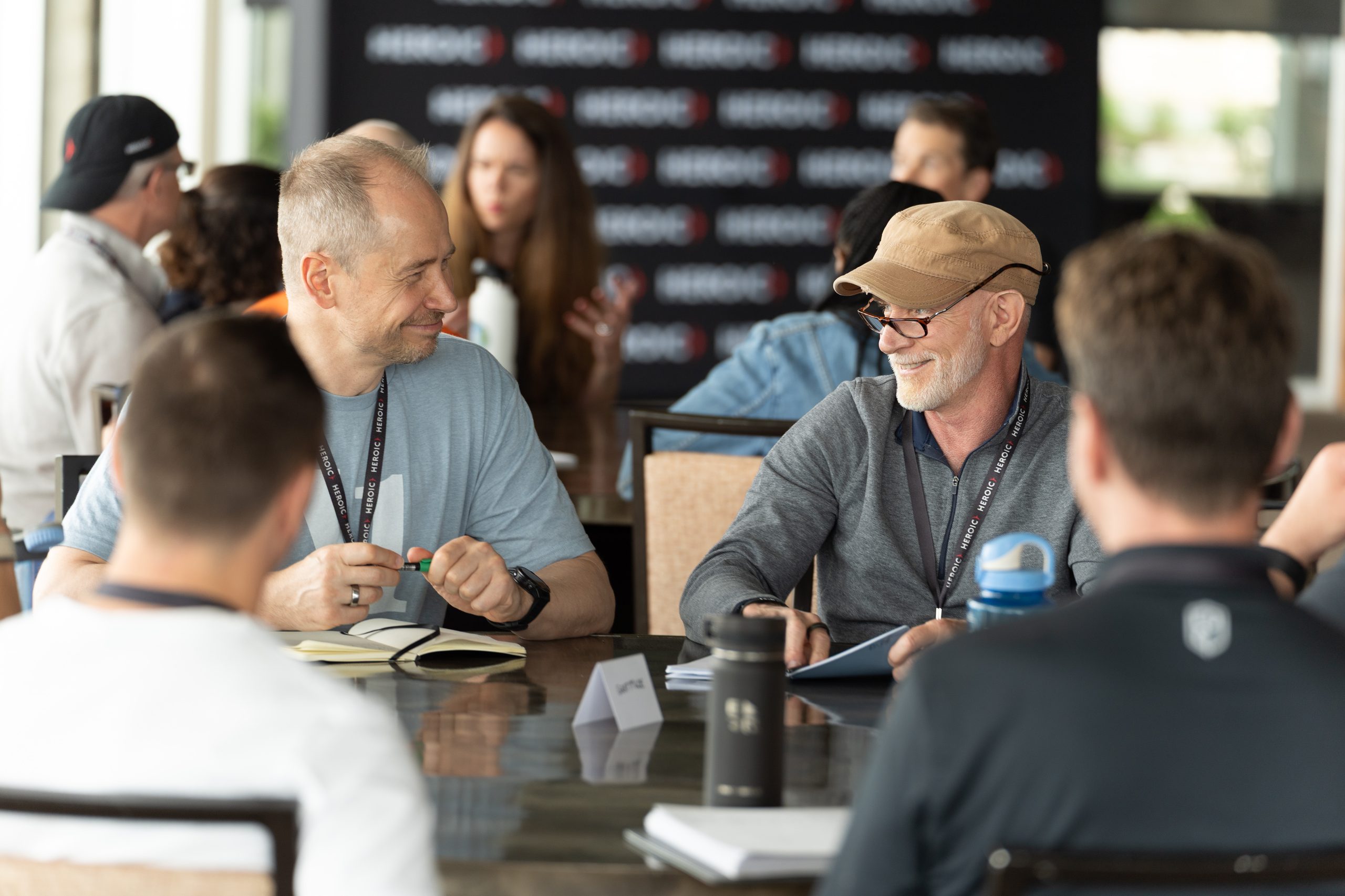 Two Heroic members in conversation at a table during a live event
