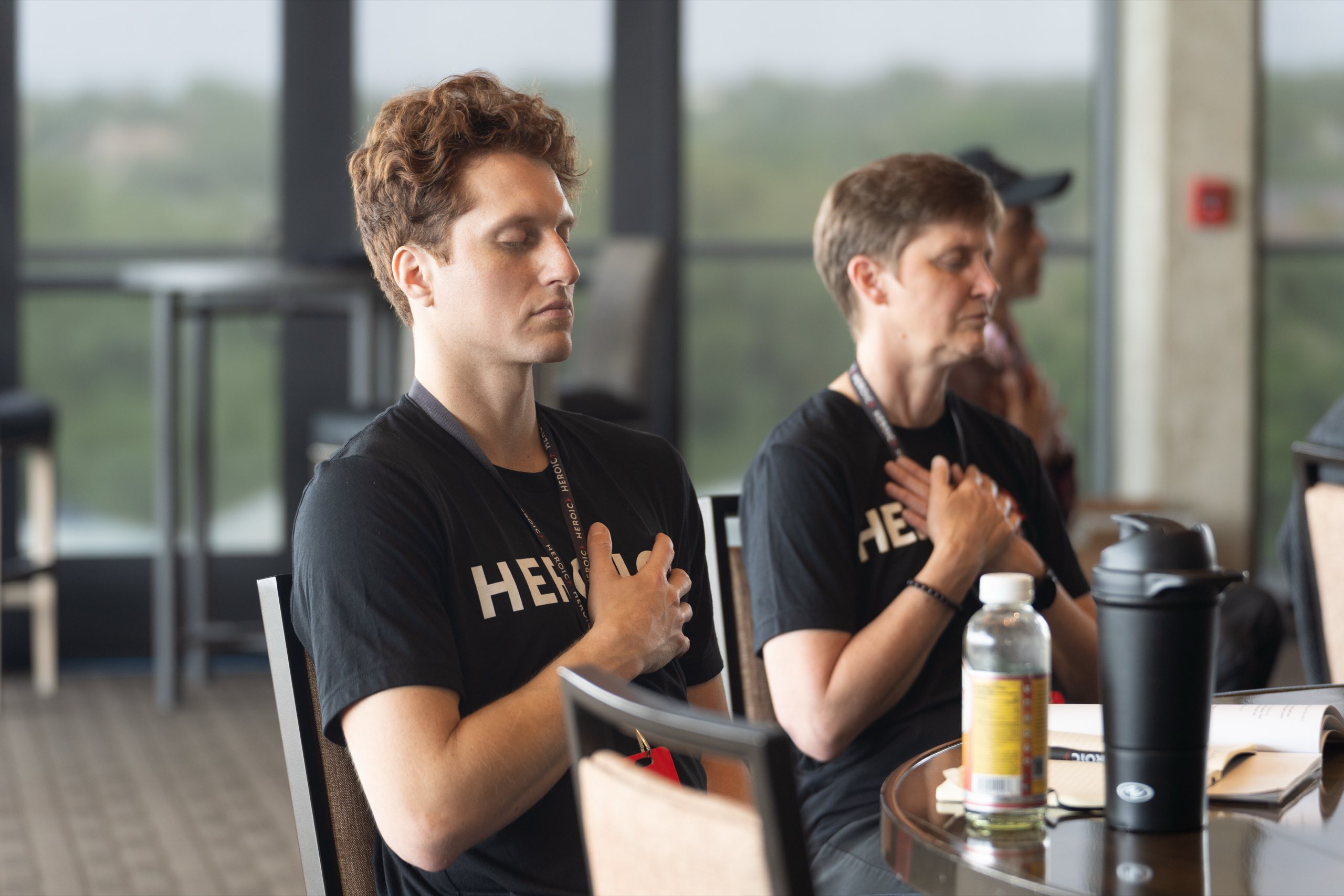Heroic members mid-practice, hands on hearts, at a live session